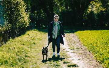 Image of person walking a dog in a field